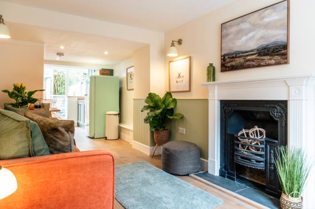 Cosy sitting room in the central Glastonbury cottage with a terracotta sofa, original fireplace and green wainscoting