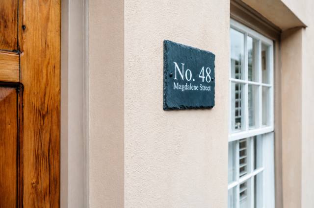 Slate house sign reading No. 48 Magdalene Street beside the front door of the Somerset holiday cottage