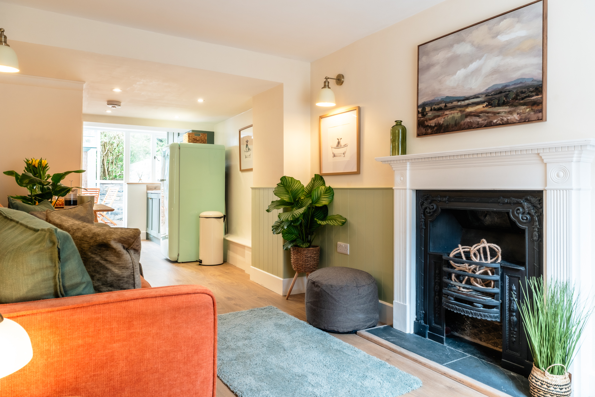 Sitting room at No. 48 Magdalene Street with a terracotta sofa, original fireplace and green wainscoting