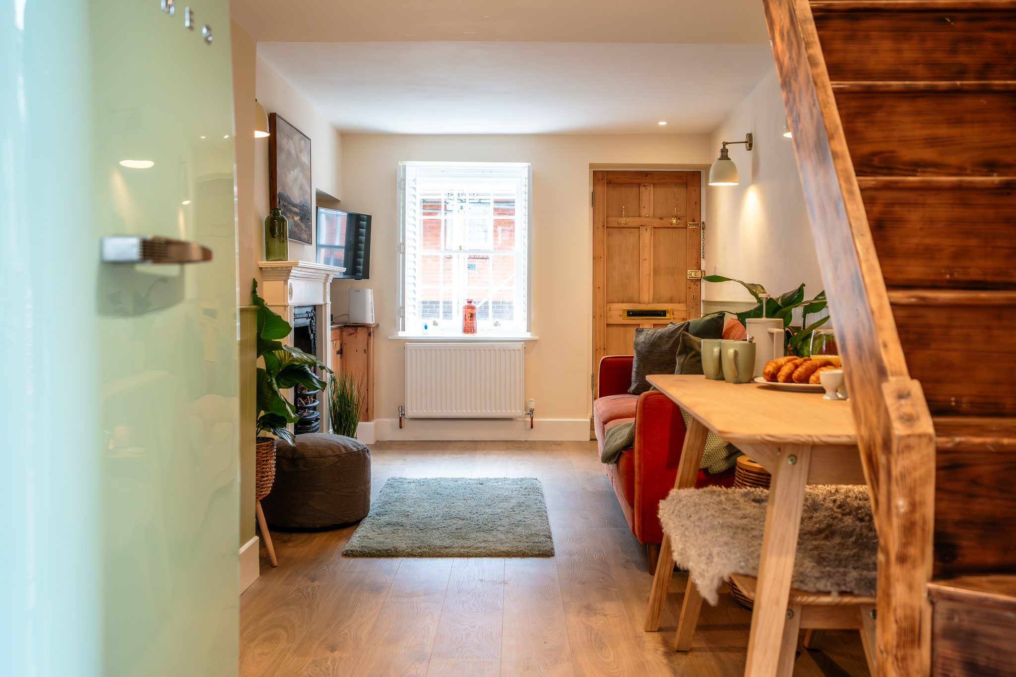 View from the kitchen at No. 48 Magdalene Street past the breakfast table and staircase to the front door, with the fireplace and shuttered window beyond