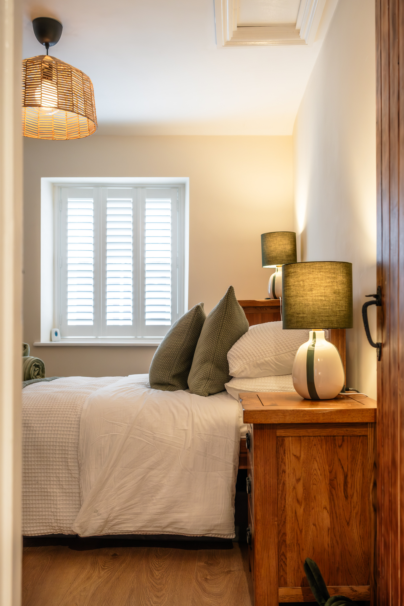Bright double bedroom at No. 48 Magdalene Street with green cushions and bedside lamps